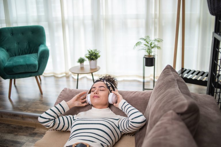 Junge Frau hört geführter Meditation über Kopfhörer zu